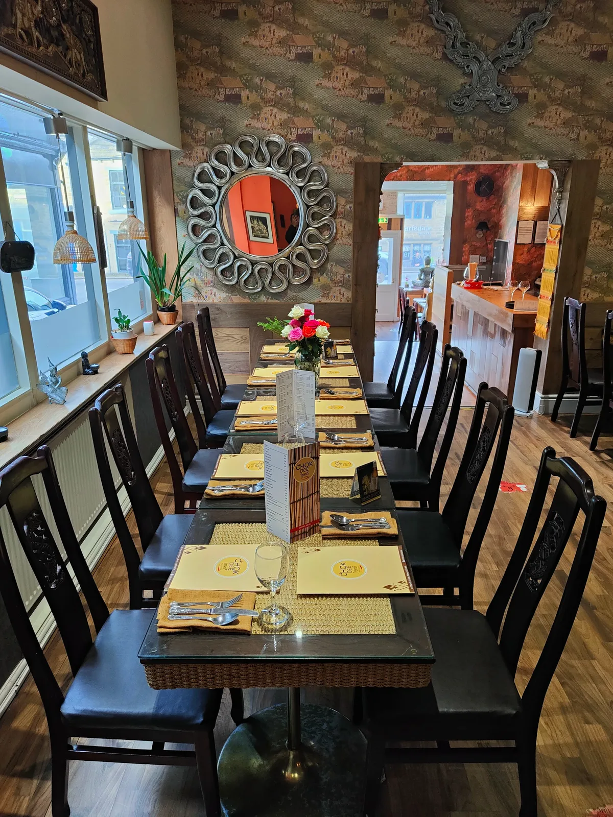 The Chokdee dining room with long wooden tables, mirrors and set places